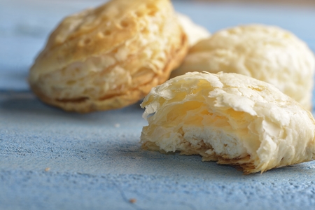 Mini cheese filled baked pies isolated on blue wooden backgroundの写真素材