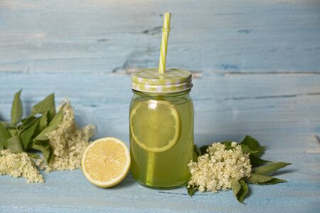 Elderberry flower flavored summer refreshment cocktail with sliced lemon isolated on wooden tableの写真素材