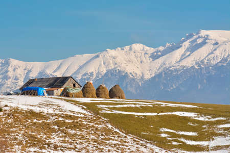 Peaceful rural landscape with traditional Romanian mountainous farm with old barn and haystacks, near Bucegi massifの写真素材