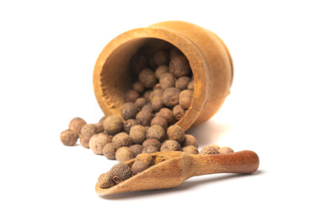 Dried herb, allspice in the olive wood scoop, isolated on whiteの写真素材