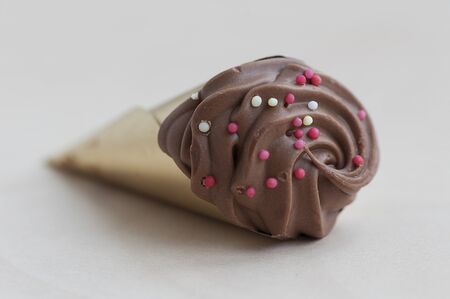 Closeup of a chocolate cone isolated on a wooden tableの写真素材