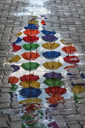 Reflection of umbrellas in a puddle on the street. Umbrella passage.の写真素材