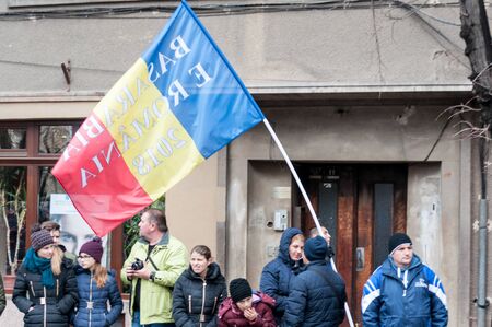 TIMISOARA, ROMANIA - DECEMBER 1, 2017: Man with a slogan on a big flag marching at the National Day parade in Romaniaのeditorial素材