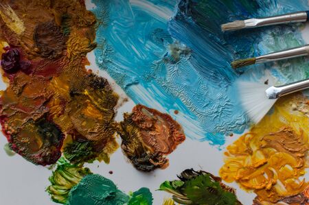 Close-up of artist brushes and colored paints on a white paletteの写真素材