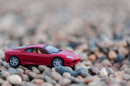 Red modern toy car on gravel. Shallow depth of field.の写真素材