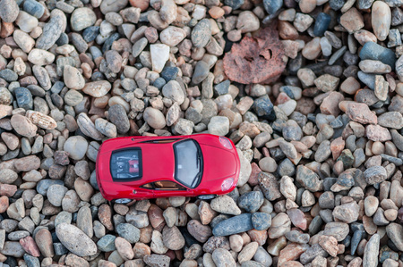 Red modern toy car on gravel. Shallow depth of field.の写真素材