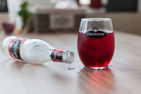 TIMISOARA, ROMANIA - JANUARY 04, 2018: Strongbow bottle and glass on a wooden table. Apple cider. Red berries.のeditorial素材