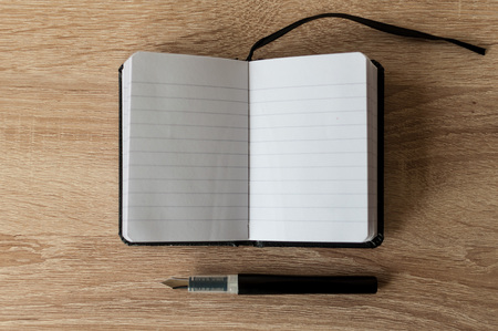 Fountain pen on a notebook. Wooden table. Copy space.