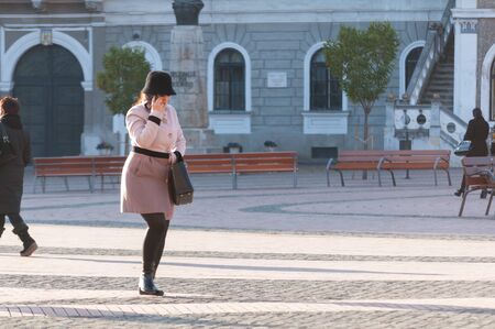 TIMISOARA, ROMANIA - NOVEMBER 29, 2016: Woman walking on the street, talking on the phone. Real people.のeditorial素材