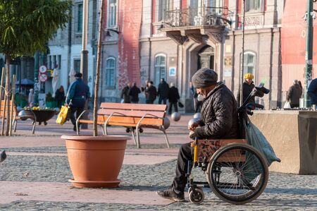 TIMISOARA, ROMANIA - NOVEMBER 29, 2016: Man in wheelchair walking on the street. Rear view. Real people.のeditorial素材
