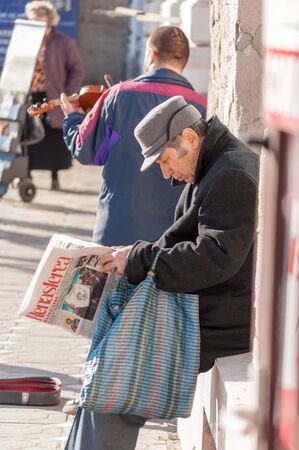 TIMISOARA, ROMANIA - MARCH 14, 2016: Man reading a newpaper (Renasterea Banateana) on the street. Real people.のeditorial素材