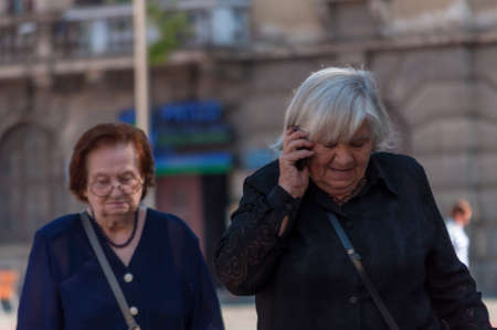 TIMISOARA, ROMANIA - SEPTEMBER 09, 2016: Woman talking on the phone and walking on the street. Real people.のeditorial素材