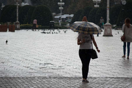 Woman walking on the street and holding an umbrella. Real people.のeditorial素材
