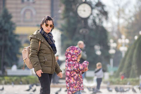 TIMISOARA, ROMANIA - NOVEMBER 17, 2019: Mother and daughter walking on the street. Real people.のeditorial素材
