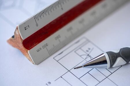 Close-up of a wooden ruler with a blueprint and mechanical pencil in the background. Architect...
