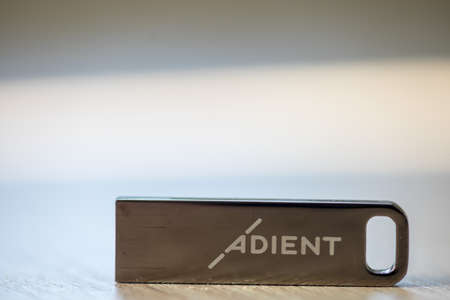 TIMISOARA, ROMANIA - JUNE 24, 2019: Close-up of a pen drive, flash disk sitting on a disk drive. Adient logo.のeditorial素材