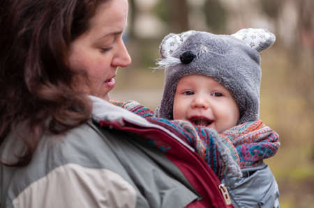 Portrait of a mother and her baby. Mother keeping her baby worm with her jacket. Baby inside cloth...