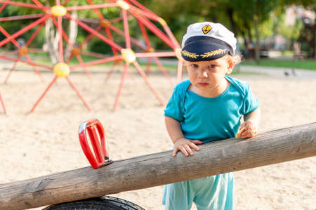 Child playing in the sand at a playground. Captain's hat.