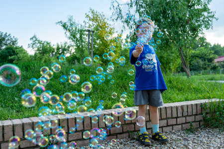 Child playing with soap bubble gun toy. Selective focus.