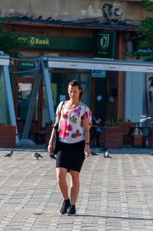 Timisoara, Romania - June 13, 2017: Woman walking on the street and drinking coffee. Real people.のeditorial素材