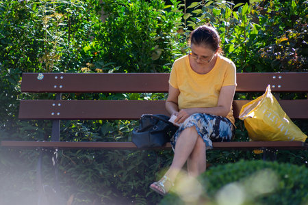 Timisoara, Romania - September 05, 2020: Woman sitting on a bench in a park. Real people.のeditorial素材
