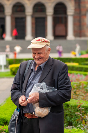 Timisoara, Romania - May 07, 2015: Man feeding pigeons  on the street. Real people.のeditorial素材