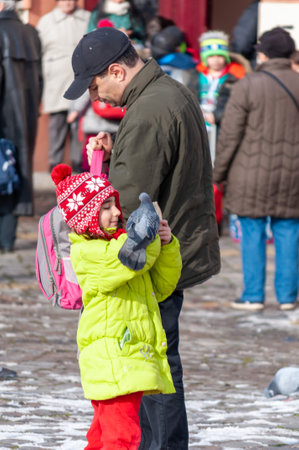 Timisoara, Romania - January 30, 2014: Kid playing with a pigeon in the street. Real people.のeditorial素材