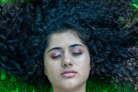 Timisoara, Romania - June 30, 2019: Portrait of a girl with curly hair lying down on the grassのeditorial素材