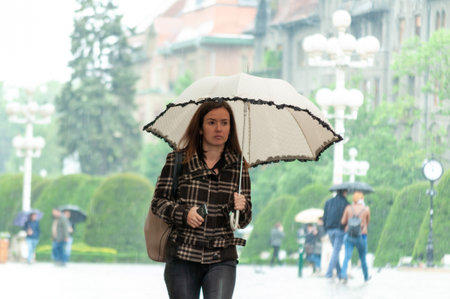 Timisoara, Romania - May 03, 2016: Woman with umbrella walking on the street. Real people.のeditorial素材