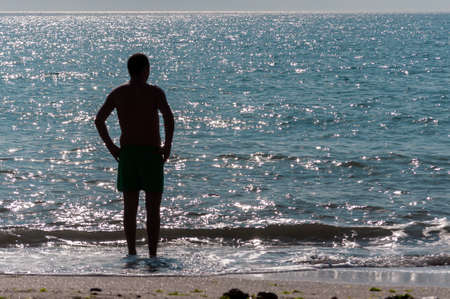 Silhouette of people walking on the beach. Unrecognisable people. Focus on the seaの写真素材