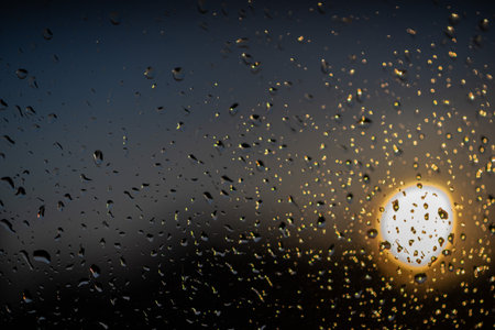 Raindrops on a window, sundown in the backgroundの写真素材