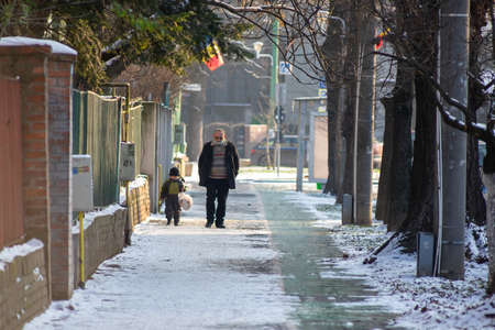 Timisoara, Romania - January 18, 2021: Man walking on the street with his grandson. Real people.のeditorial素材