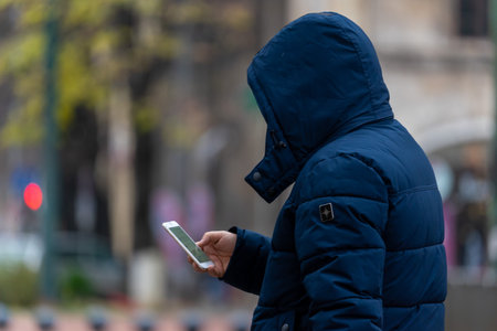 Man walking and checking his phone on the street. Real people.の写真素材
