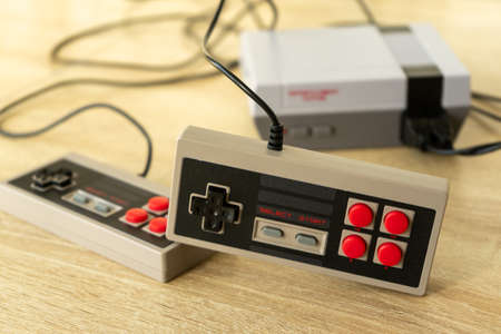 Retro gaming console with classic gamepad controller on a wooden tableの写真素材