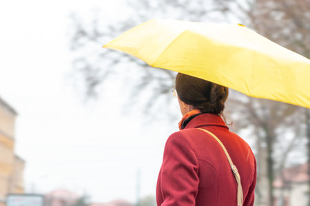 Woman walking on the street in the rain with an umbrella in hand. Real people.