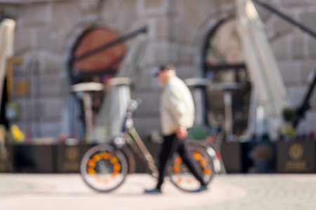 Man walking on the street alongside his bicycle. Blurred image