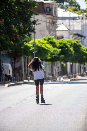 Girl with roller skates riding on the street on a sunny day.の写真素材