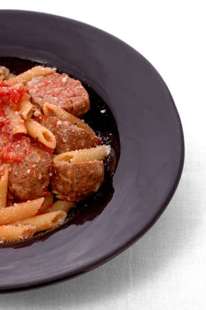 Plate of meatballs with sauce and penne pasta, cheese sprinkled on top.の写真素材