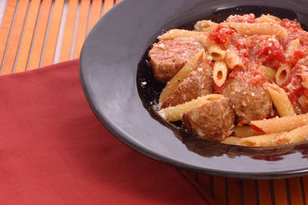 Plate of meatballs with sauce and penne pasta, cheese sprinkled on top.の写真素材