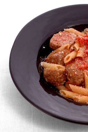 Plate of meatballs with sauce and penne pasta, cheese sprinkled on top.の写真素材