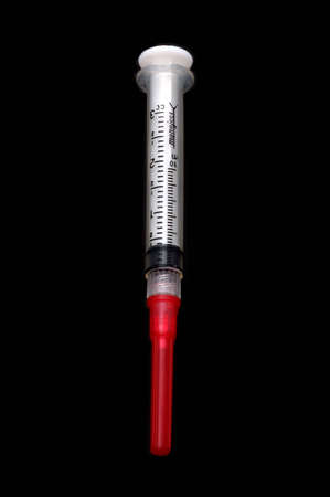 A 3cc syringe with a short needle (capped), isolated over blackの写真素材
