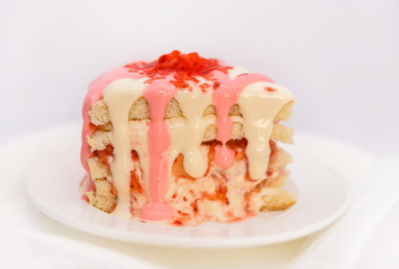 Biscuit with a filling of berries and cream, soft curd, on a white plate and sprinkled with white chocolateの写真素材