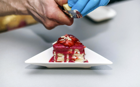 Biscuit with a filling of berries and cream, on a white plate and sprinkled with white chocolate