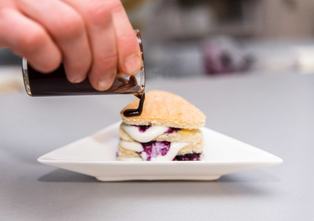 Chocolate biscuit with a filling of berries and cream, on a white plate.の写真素材