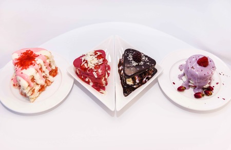 Cakes with berry stuffing on a white plate are sprinkled with different chocolates