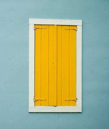 Yellow Shutters on Window on Blue Stucco Wallの写真素材