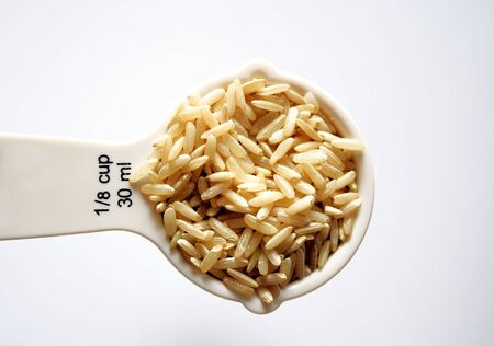 Nutritious wholegrain brown rice in measuring cupの写真素材