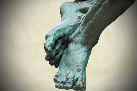 Bronze sculpture of feet - distressed background with vignette borderの写真素材