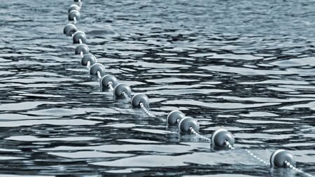 Buoys strung together by rope along lake to create safe swimming area for swimmersの写真素材