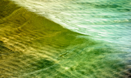 Waters with soft waves in green and goldの写真素材